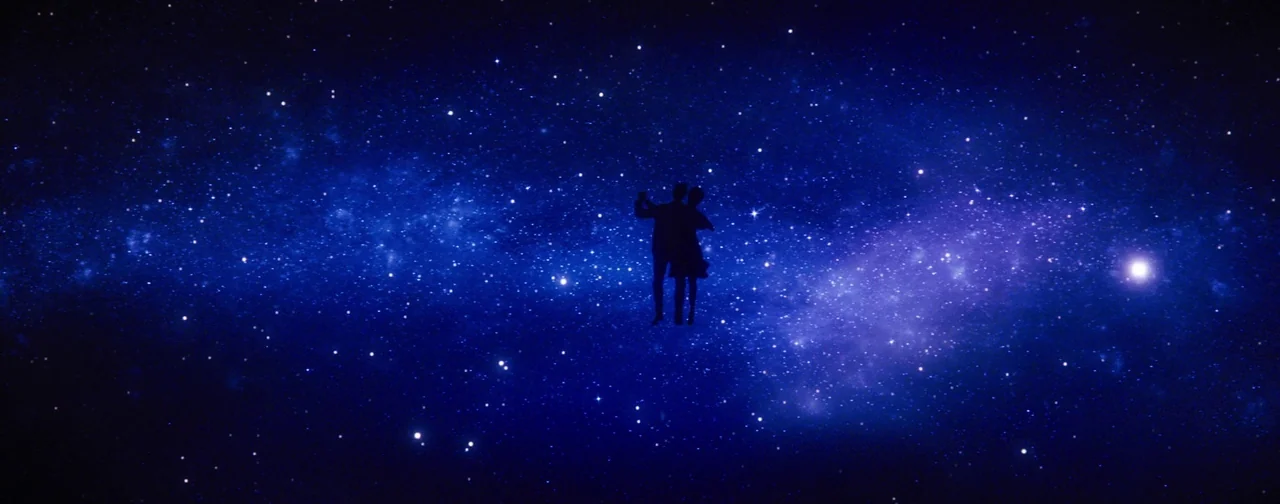 La La Land (2016) movie still: wide — Two human figures appear as silhouettes suspended against a vast, star-filled nebula. The pair is positioned…