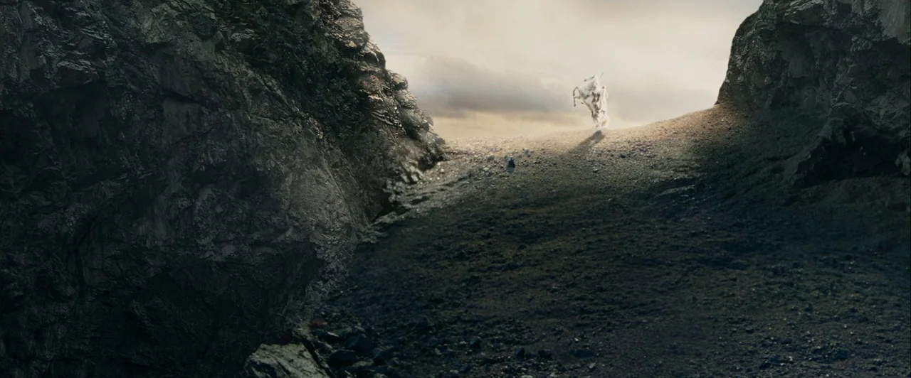 The Lord of The Rings: The Two Towers (2002) movie still: wide — A narrow mountain pass is flanked by large, dark, craggy rock formations on both…