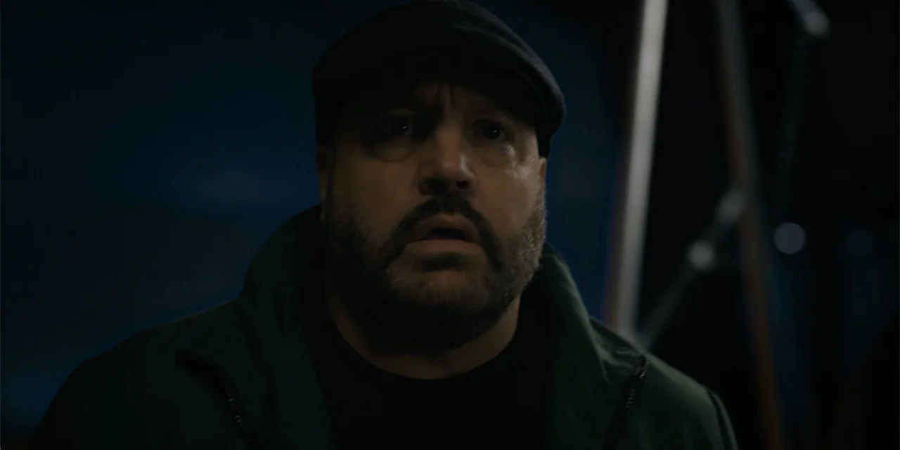 Playdate (2025) movie still: closeup — A man stands in a dark outdoor setting at night. He stares forward with an open mouth expression.