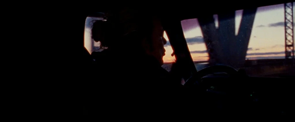 The Wrestler (2008) movie still: medium — The interior of a vehicle at dusk with a view of a bridge structure. A man is driving while the sun sets…