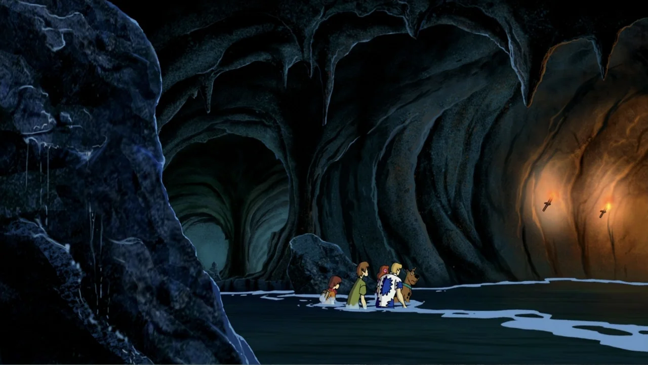 Aloha Scooby-Doo! (2005) movie still: wide — An underground limestone cavern features dark rock walls and a pool of shallow water. A group of…