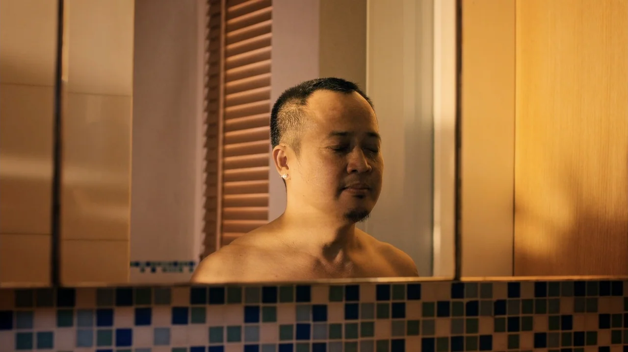 Zero Tolerance (2015) movie still: medium — A tiled bathroom features a wall-mounted mirror above a mosaic tile backsplash. A shirtless man stands…