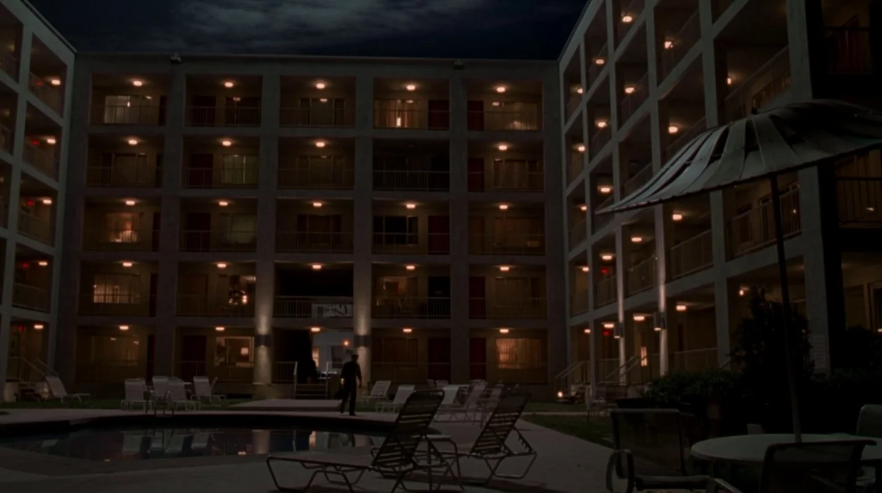 Lady in the Water (2006) movie still: establishing — A multi-story residential building surrounds an empty swimming pool and outdoor lounge…