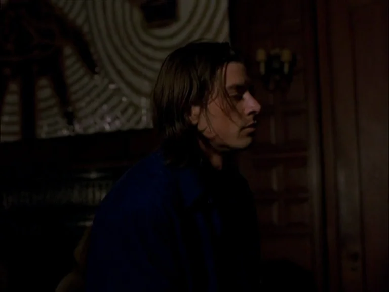 Last Days (2005) movie still: medium — A dimly lit room features wood-paneled walls and a circular patterned wall art piece. A young man sits in the…