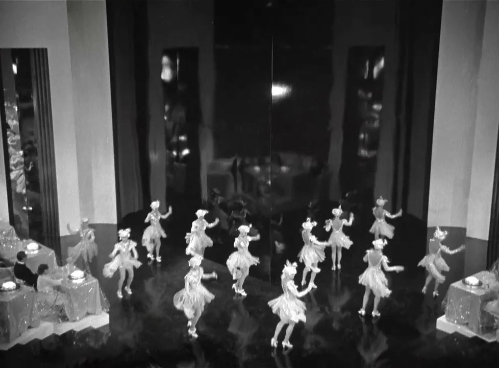 Swing Time (1936) movie still: wide — A spacious dance floor features a large central reflective wall panel with black flooring. Numerous dancers in…