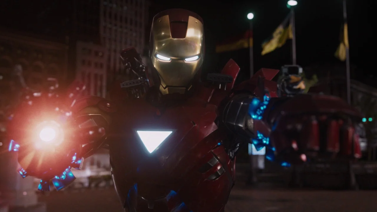 The Avengers (2012) movie still: medium — A dark city square at night featuring blurred urban buildings and tall flagpoles. A mechanical armored…