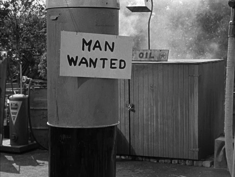 The Postman Always Rings Twice (1946) movie still: medium — A vintage gas station exterior features a weathered pump with a hand-lettered sign. A…