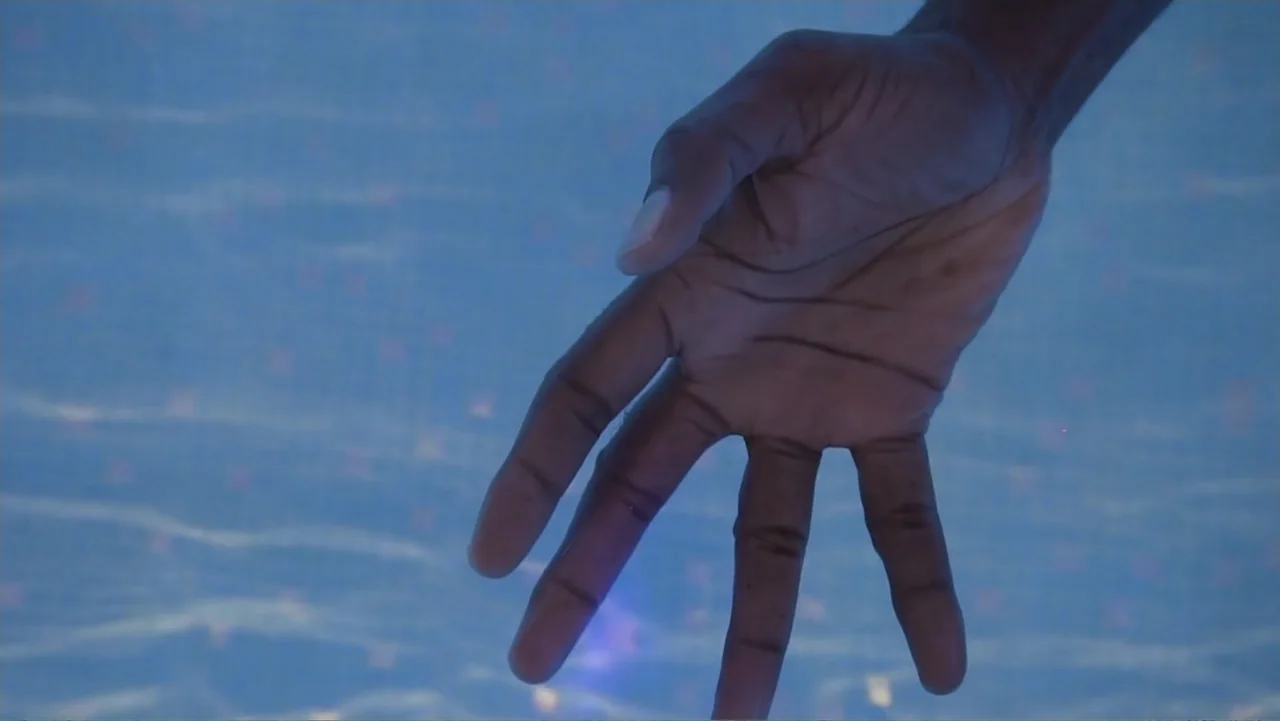 A Film Called Blacks Can't Swim (My Journey My Story) (2020) movie still: closeup — A close-up view shows a hand submerged beneath the surface of…