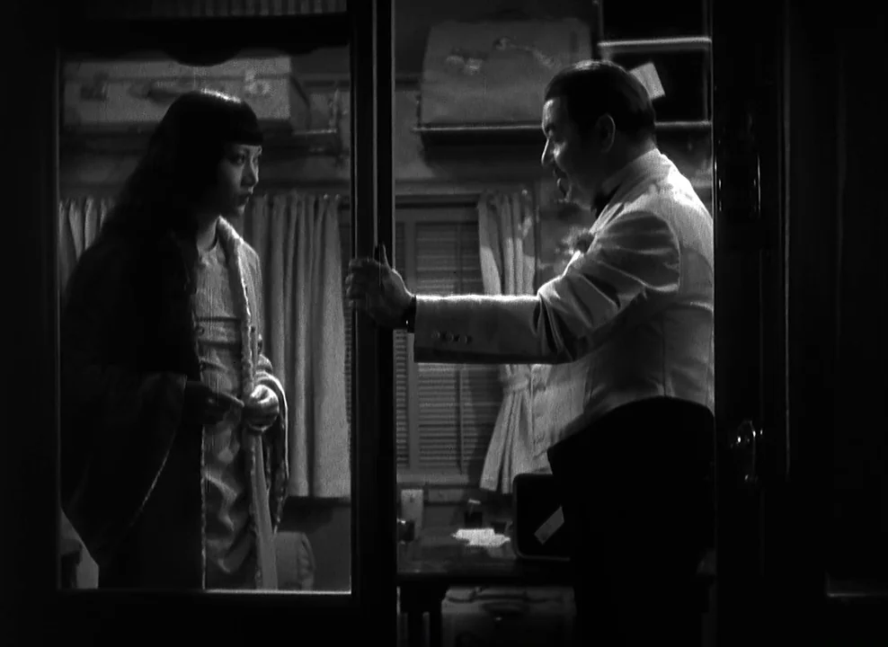 Shanghai Express (1932) movie still: medium — A vintage train cabin at night features luggage racks and small windows with curtains. A woman in a…