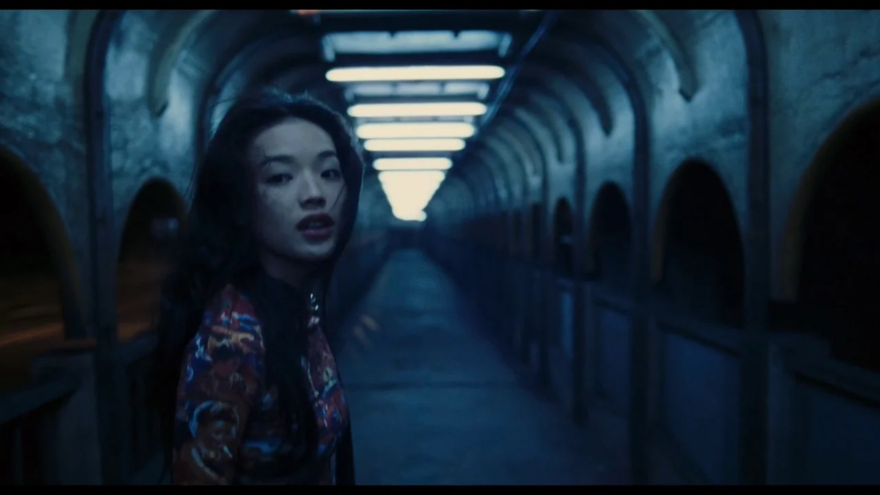 Millennium Mambo (2001) movie still: medium — A long, dimly lit pedestrian tunnel features rows of vaulted arches along both walls. A young woman…
