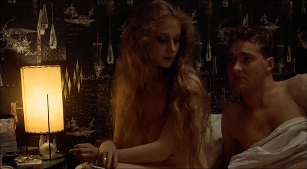 The Last Detail (1973) movie still: medium — A dimly lit room features patterned dark wallpaper and a single table lamp. A man and a woman sit in…