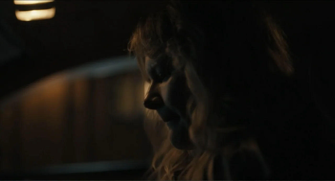 Hell of a Summer (2025) movie still: closeup — A dark vehicle interior with a single overhead light providing dim illumination. A woman with…