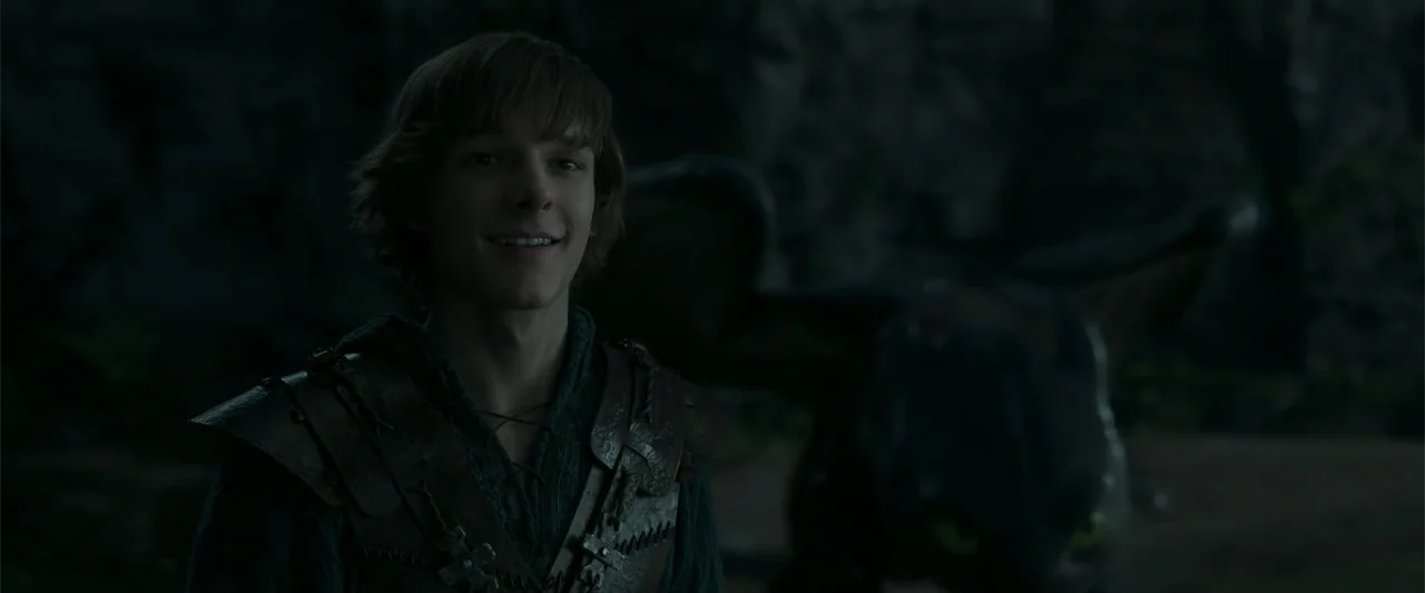 How to Train Your Dragon (2025) movie still: medium — A dimly lit rocky interior with dark stone walls surrounding the subject. A young man wearing…