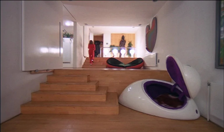 A Clockwork Orange (1971) movie still: wide — A modernist residence interior features split-level wooden flooring and stark white walls. A person…