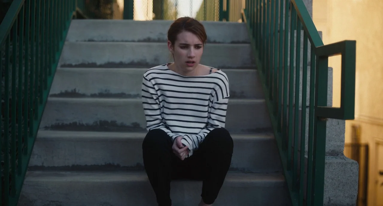 Palo Alto (2013) movie still: medium — A woman sits on the concrete steps of an outdoor staircase. The staircase features green painted metal…