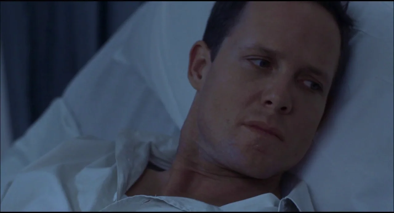 Hellraiser: Hellseeker (2002) movie still: closeup — A man lies on a white pillow in a dimly lit, cool-toned setting. He looks away from the camera…