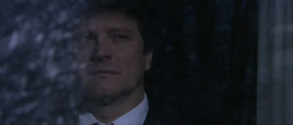 Genova (2008) movie still: closeup — A man looks through a window at night, his reflection visible against dark surroundings. He stands silently by…