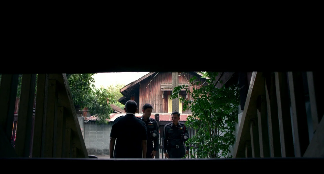 Only God Forgives (2013) movie still: fullbody — A wooden house with a weathered facade stands behind three officers in uniform. The men stand in a…