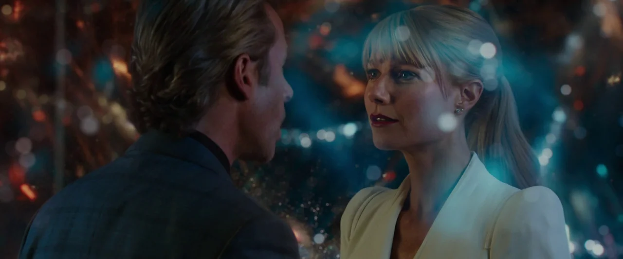 Iron Man 3 (2013) movie still: medium — A man and a woman stand close to each other in a dark environment. They are surrounded by numerous colorful,…