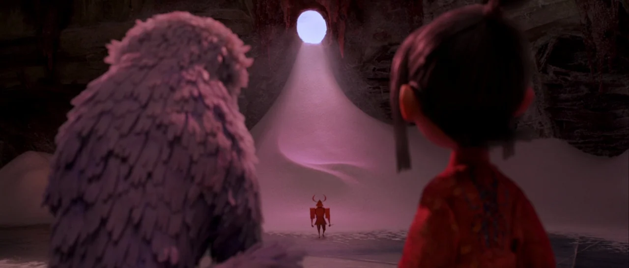 Kubo and the Two Strings movie still: medium — A dark rocky cave interior features a large mound of white snow. A small samurai figure stands in the…