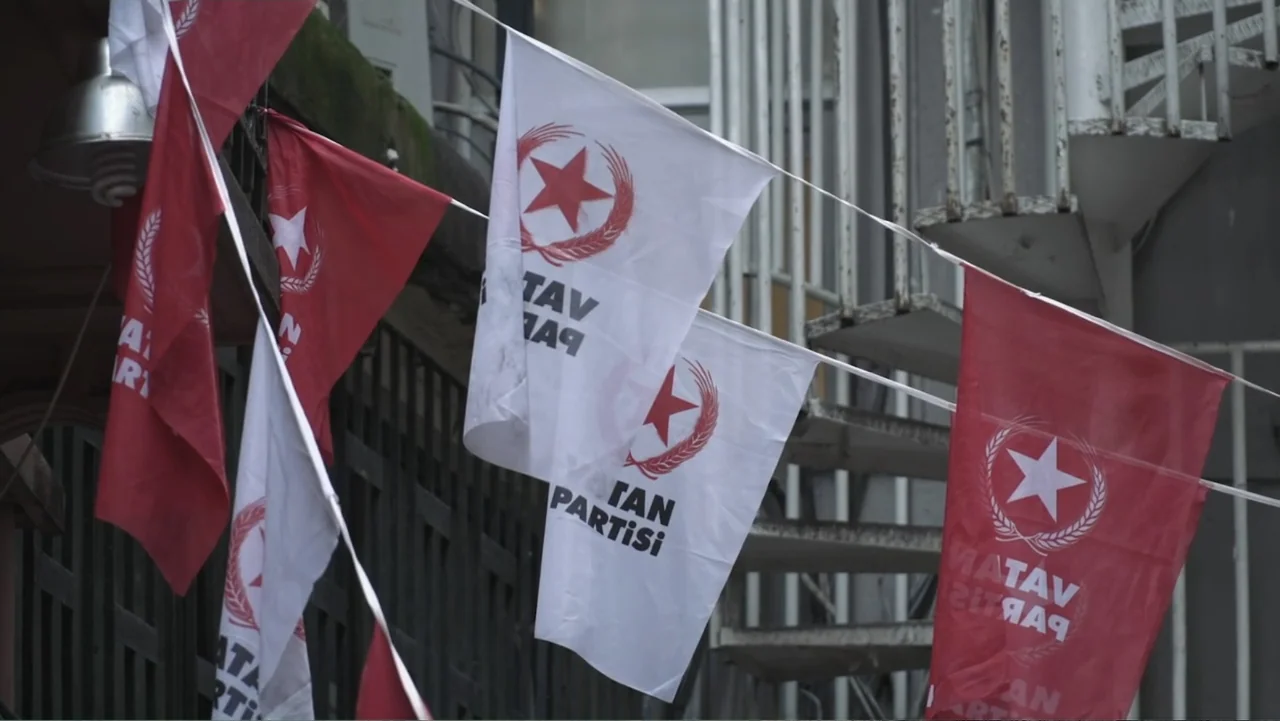 A Gift from God (2019) movie still: medium — White and red political flags with symbols are suspended in an outdoor urban area. A metal staircase…