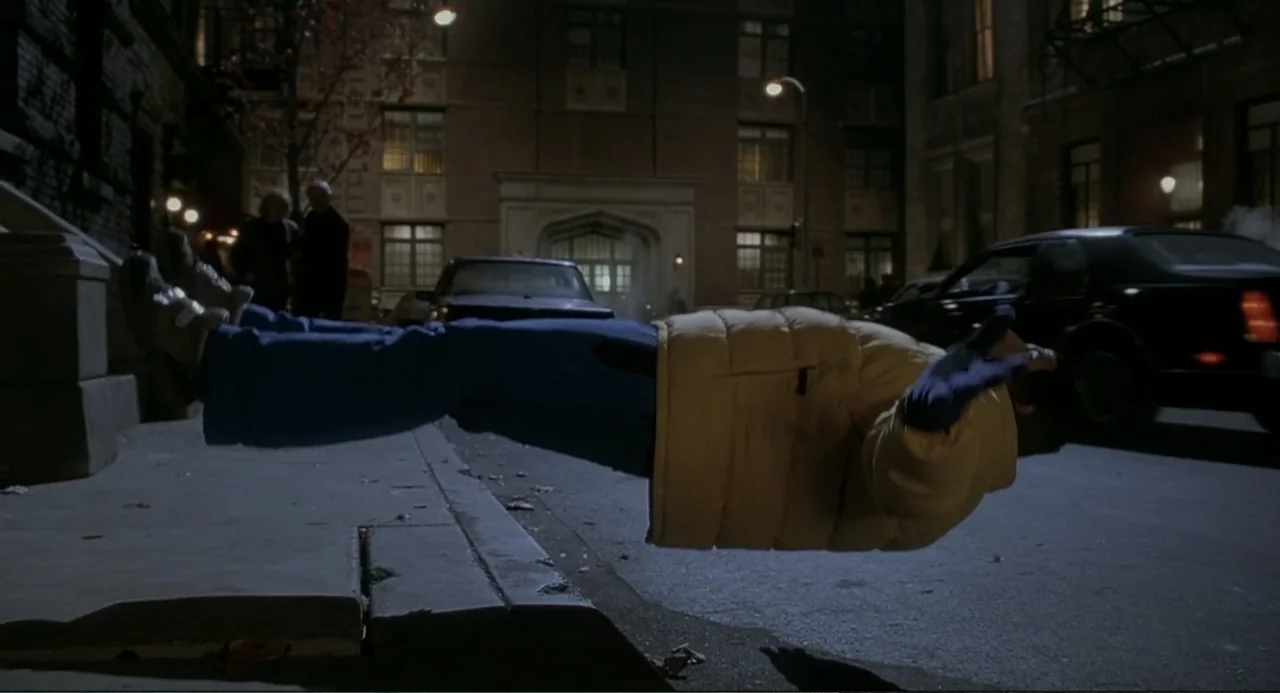 Little Nicky (2000) movie still: medium — An urban sidewalk at night features brick apartment buildings and a parked sedan. A man floats…