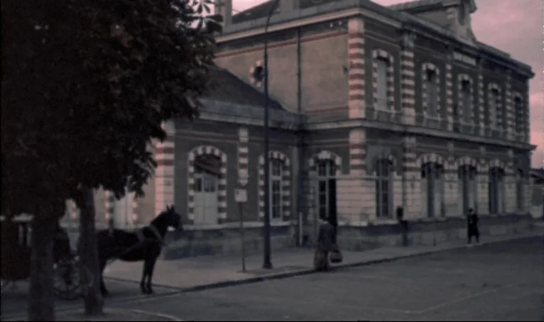 The Thief of Paris (1967) movie still: wide — A historic stone railway station building features red and white striped brick detailing. A…