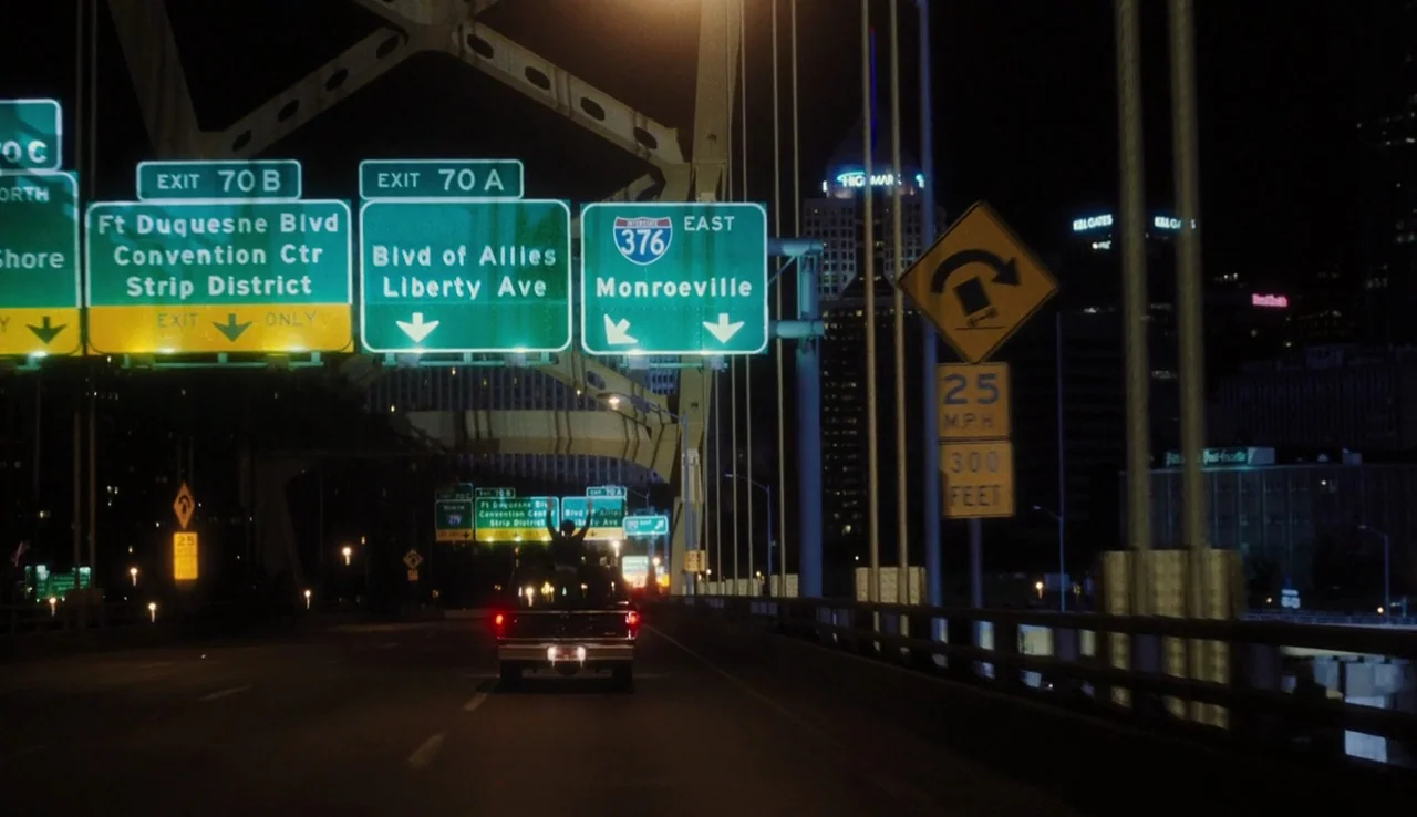 The Perks of Being A Wallflower (2012) movie still: wide — A night view on a bridge featuring multiple large illuminated green highway direction…