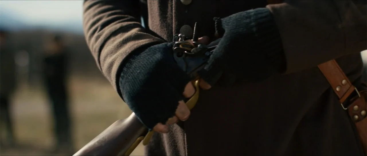 Out of Liberty (2019) movie still: closeup — An open outdoor field serves as the backdrop for a close-up historical depiction. Hands wearing black…