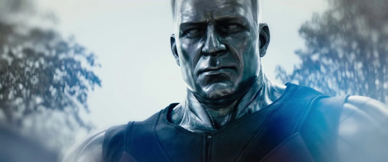 Deadpool 2 (2018) movie still: closeup — A close up of a humanoid figure with metallic skin in a forest setting. The figure looks forward with a…
