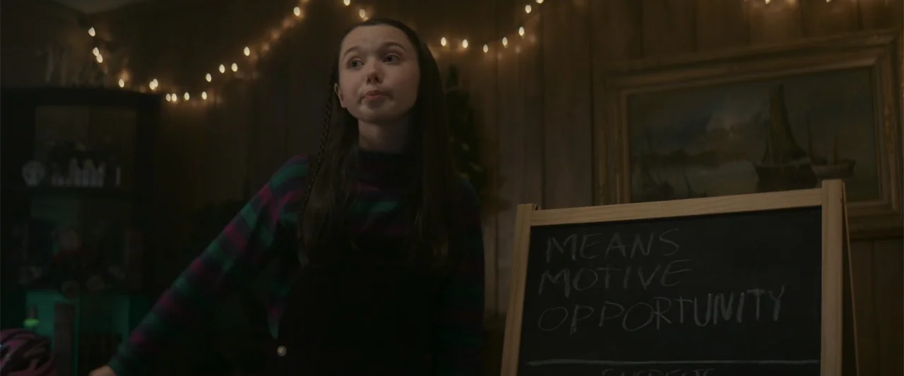 A Christmas Mystery (2022) movie still: medium — A dimly lit indoor space with wooden wall paneling and hanging string lights. A young girl stands…