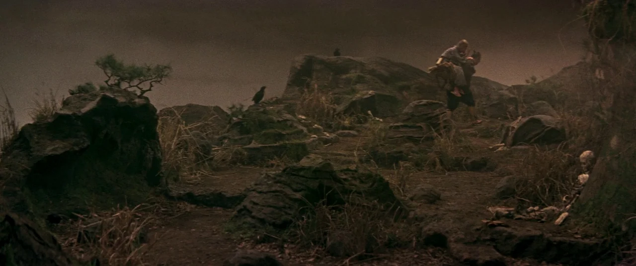 Ballad Of Narayama (1958) movie still: wide — A barren, rocky landscape features sparse dry grass and scattered volcanic-like rock formations. A…
