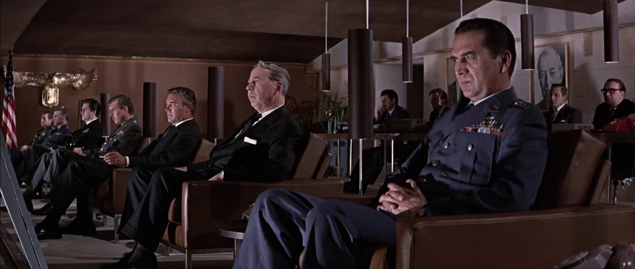 You Only Live Twice (1967) movie still: wide — A 1960s wood-paneled briefing room with rows of brown leather armchairs and hanging cylindrical…