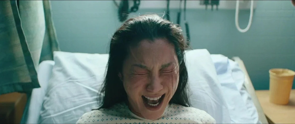 Everything Everywhere All At Once (2022) movie still: closeup — A hospital room with mint-green walls and a patient bed with white linens. A woman…