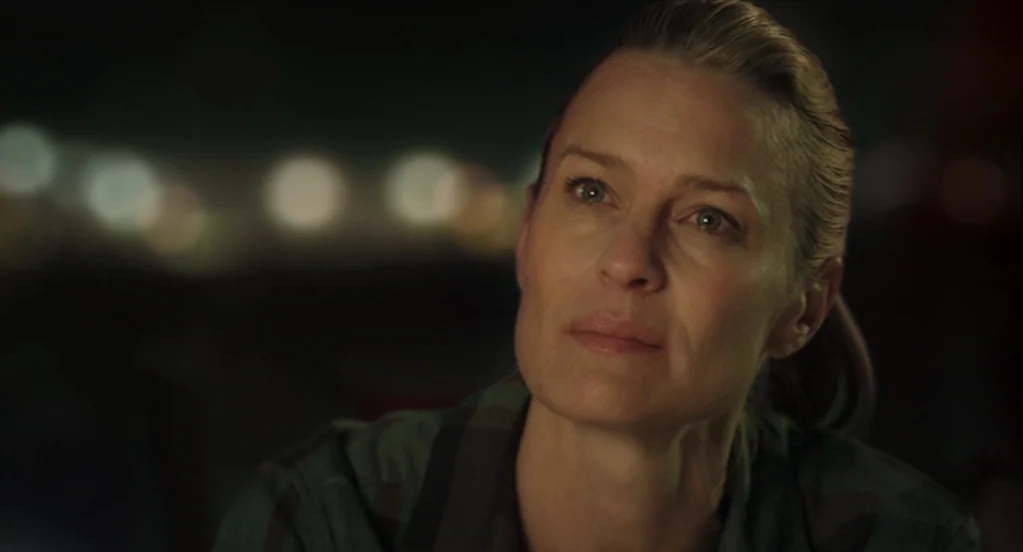 The Congress (2013) movie still: closeup — An out-of-focus urban background with blurred light orbs at night. A woman is in the foreground, facing…