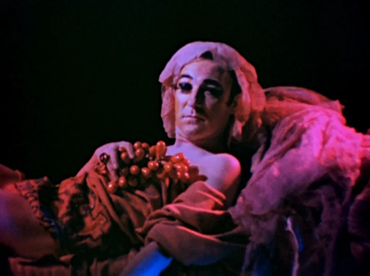 Inauguration of the Pleasure Dome (1954) movie still: medium — A man lies against a dark background illuminated by vibrant magenta light. He wears…