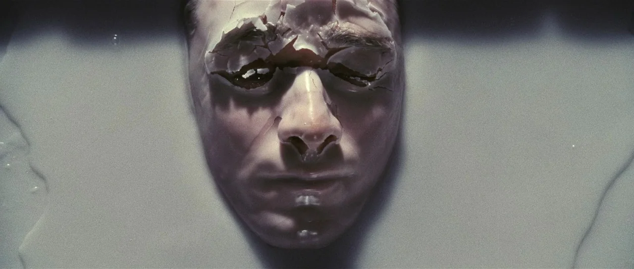 Wanted (2008) movie still: closeup — A human face is submerged in a thick, opaque gray liquid. The forehead skin displays extensive cracking…