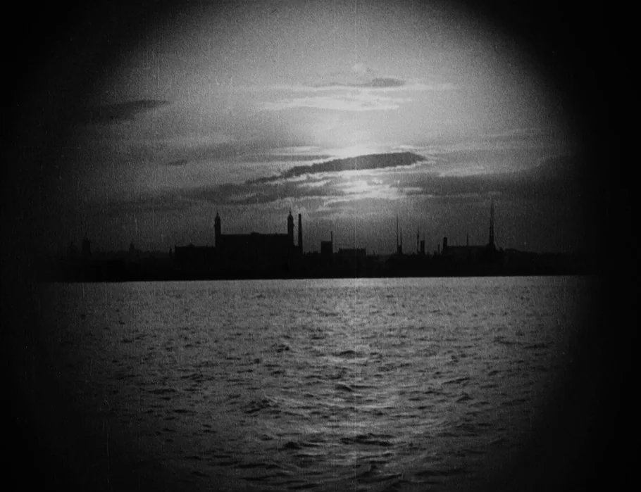 Battleship Potemkin (1925) movie still: establishing — A dark, textured silhouette of a city skyline stands against a fading sunset sky. The…