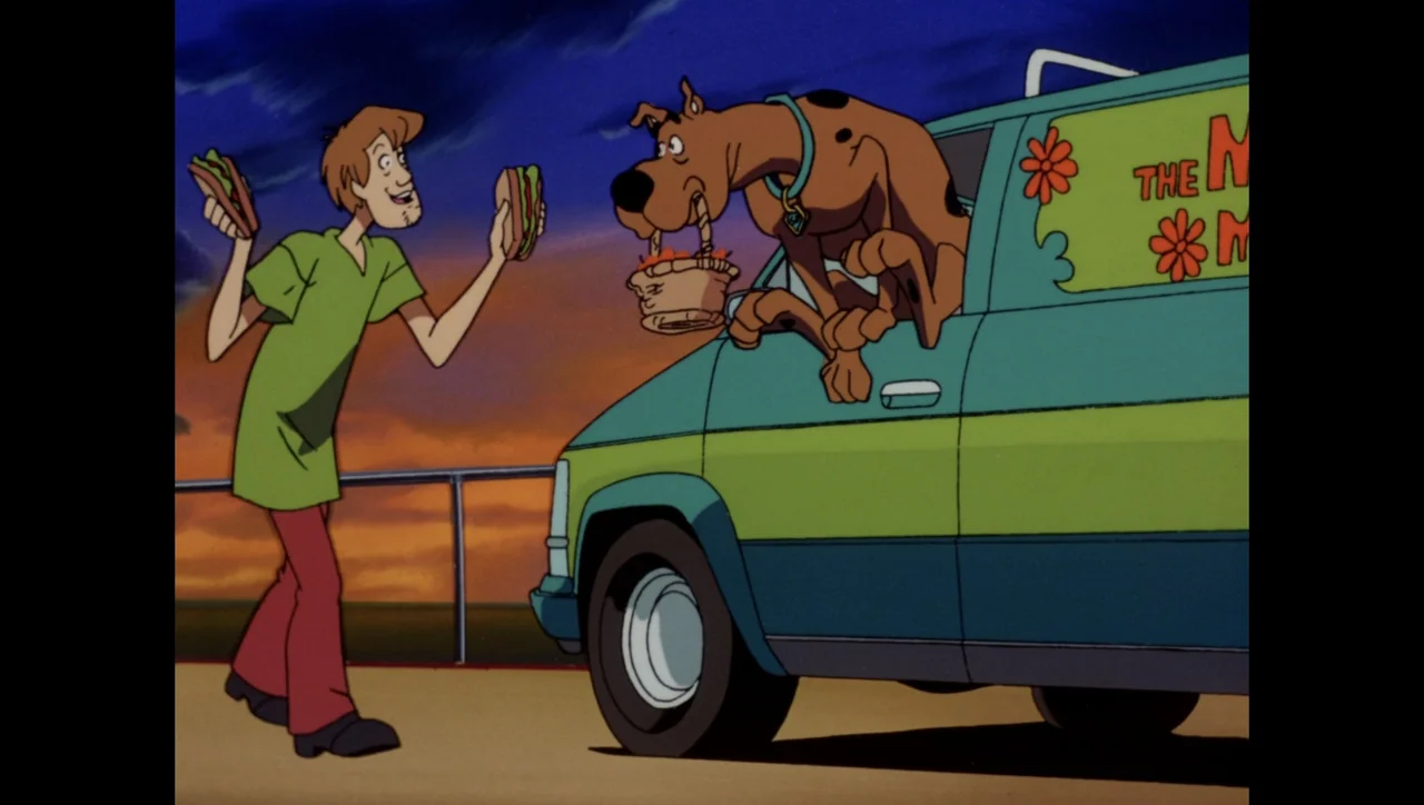 Scooby-Doo on Zombie Island (1998) movie still: fullbody — A paved area at dusk with a multicolored van parked in the foreground. A man stands…