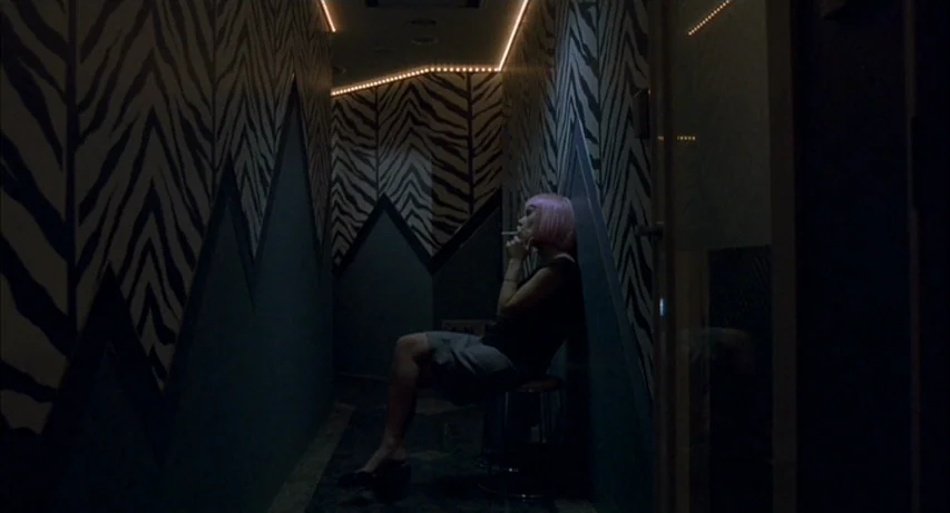 Lost In Translation (2003) movie still: medium — A narrow dimly lit corridor features walls covered in distinctive black and white zebra pattern. A…