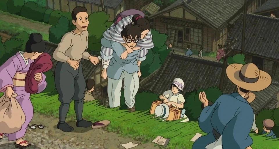 The Wind Rises (2013) movie still: wide — A group of people navigate a hillside path overlooking a small Japanese village. They carry luggage and…