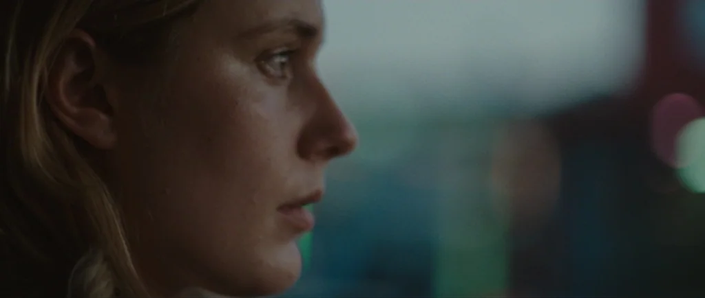 Greenberg (2010) movie still: closeup — A close-up view shows a woman's face from the side while inside a vehicle. She gazes out into the darkness…