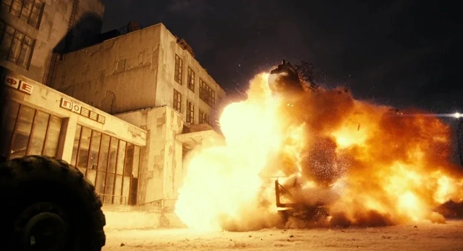 A Good Day to Die Hard (2013) movie still: wide — A weathered, multi-story concrete industrial building stands at night near a large explosion. A…