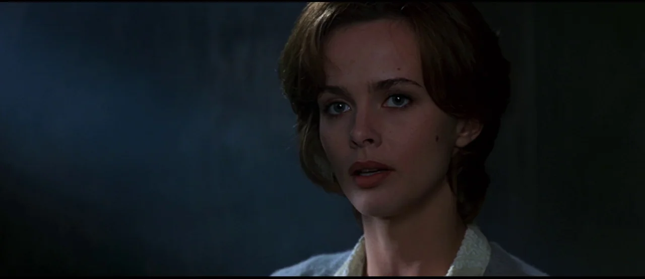 GoldenEye (1995) movie still: closeup — A dimly lit, dark space serves as the backdrop for a close-up portrait. The subject looks directly into the…