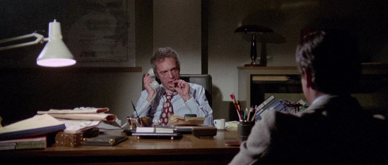 The Case of the Scorpion’s Tail (1971) movie still: medium — A cluttered executive workspace features wooden furniture and stacks of paper…