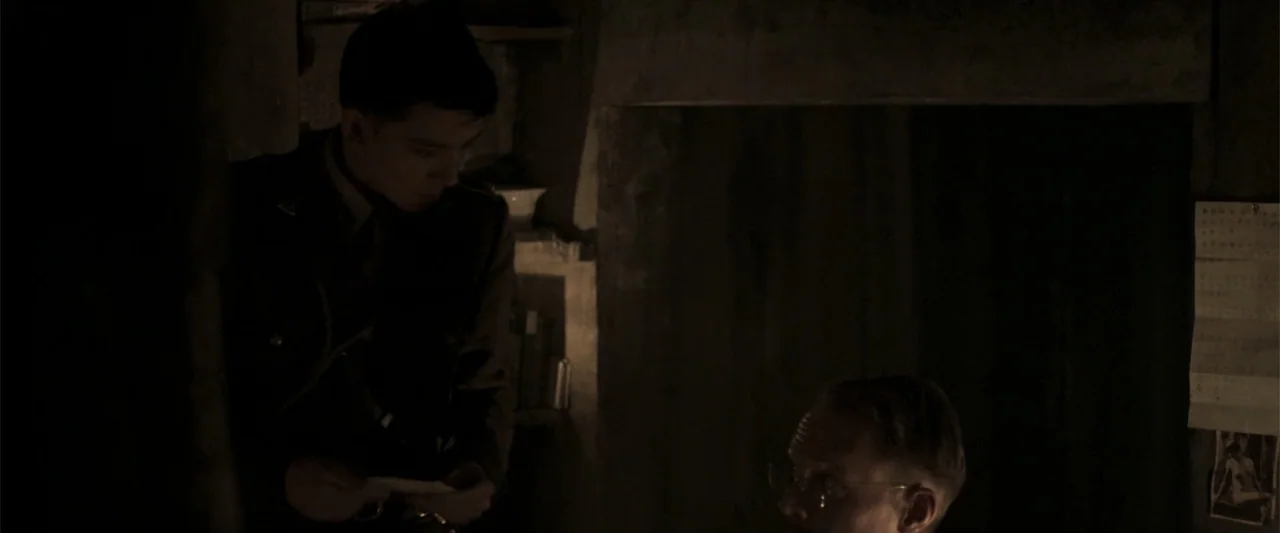 Gone Missing -  Old John's Final Journey (2014) movie still: medium — A dimly lit room features dark walls and minimal decor with a paper document…