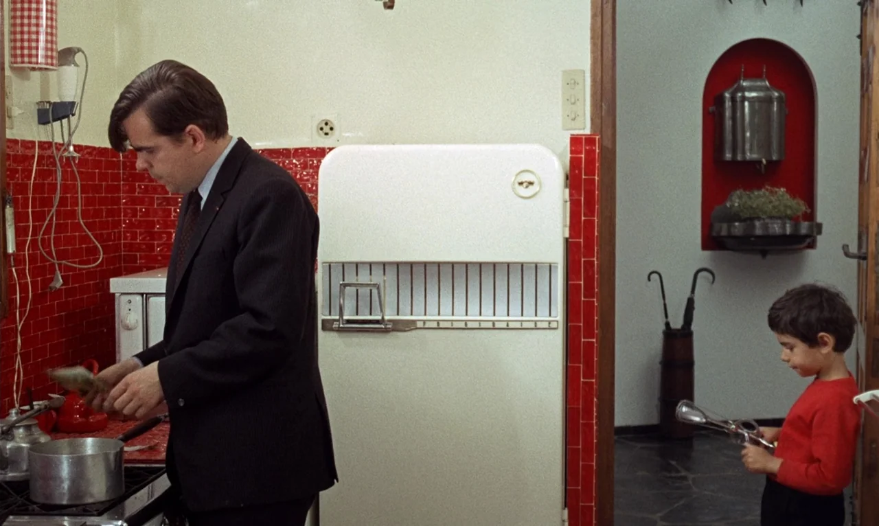The Bride Wore Black (1968) movie still: medium — A mid-century modern kitchen features glossy red tiled walls and a vintage refrigerator. A man in…