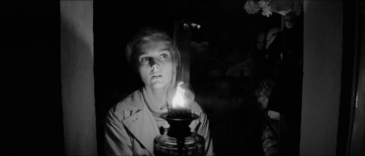 Bunny Lake Is Missing (1965) movie still: medium — A dimly lit narrow storage room features shelves packed with porcelain doll heads. A young woman…