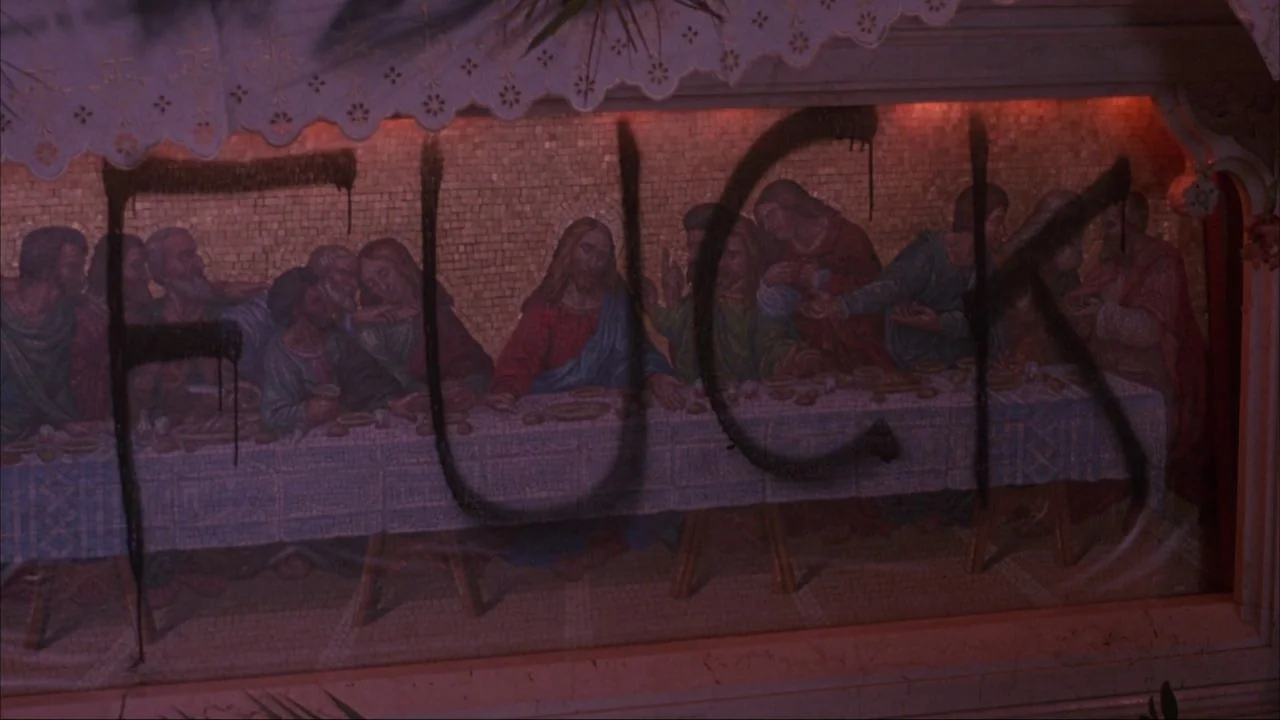 Bad Lieutenant (1992) movie still: medium — A decorative mosaic depicting the Last Supper is defaced with dark aerosol paint lettering. The word…