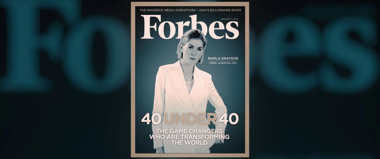 I Care A Lot (2020) movie still: medium — A magazine cover features a portrait of a woman against a dark teal background. The text displays the…